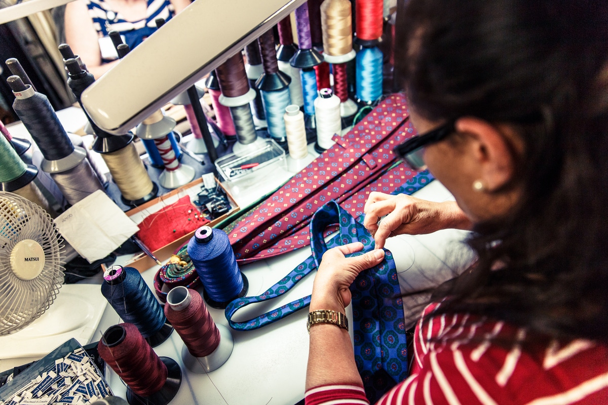 A seamstress slipstitches a tie.