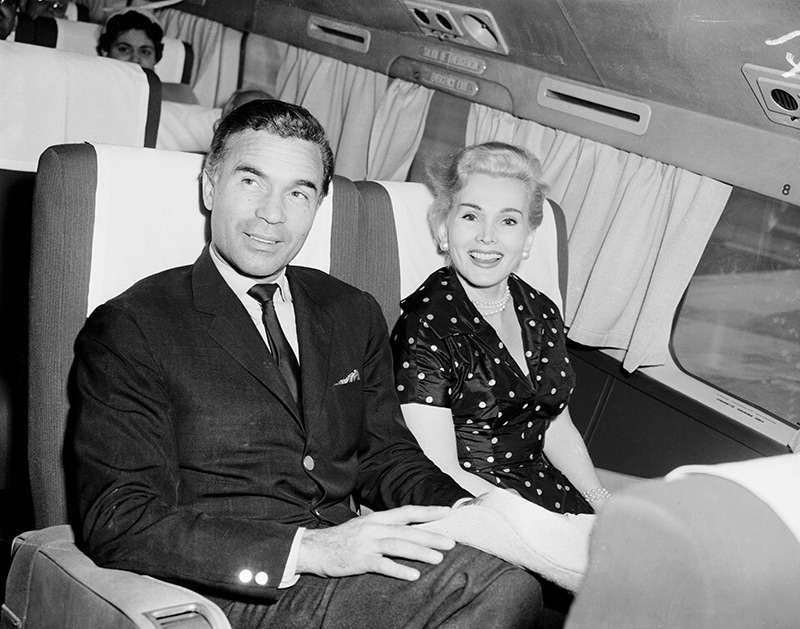 Porfirio Rubirosa and the lovely actress Zsa Zsa Gabor smile as they pass through Miami en route to the West Coast, circa 1954.