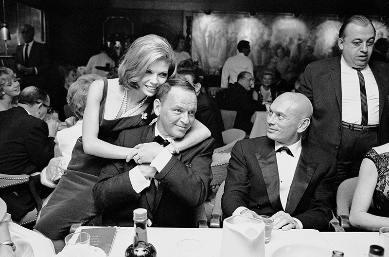 1965: Frank Sinatra getting affectionate hug from daughter Nancy as actor Yul Brynner looks on