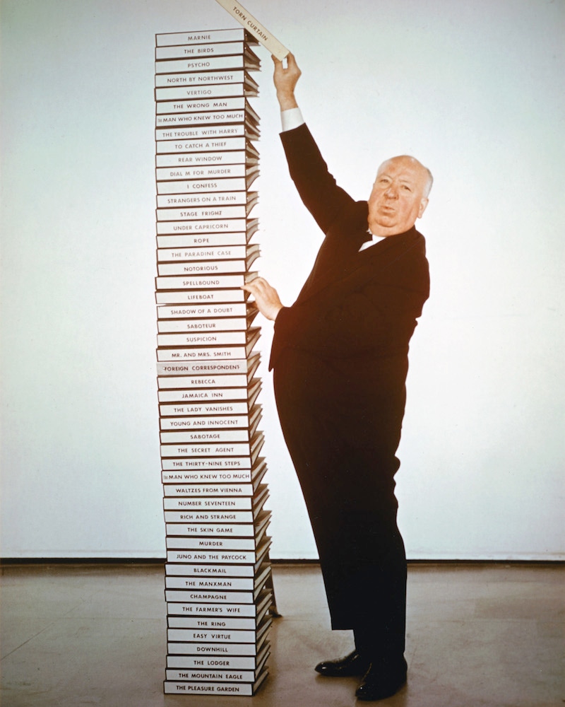 English film director Alfred Hitchcock  adds the script of his latest film 'Torn Curtain' to a pile of scripts representing his career from 1925 to 1966. Photo by Silver Screen Collection/Hulton Archive/Getty Images.