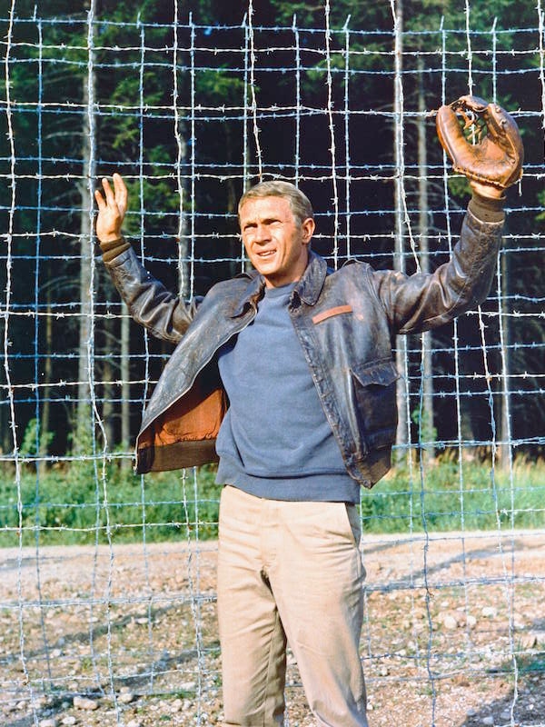 Steve McQueen wearing a leather jacket and a baseball glove, with his hands held up in submission, in a publicity still issued for the film, 'The Great Escape', 1963. Photo by Silver Screen Collection/Getty Images.