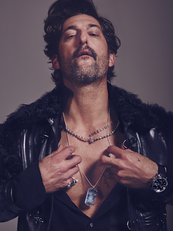 Black shearling and leather jacket, Brad Smith; black cotton knitted shirt, Ermenegildo Zegna; silver small skull chain necklace, Zoe & Morgan; large silver cross ring and silver etched dog tag with silver ball chain, both Chrome Hearts; stainless steel Grande Seconde sports watch with black rubber strap, Jaquet Droz.