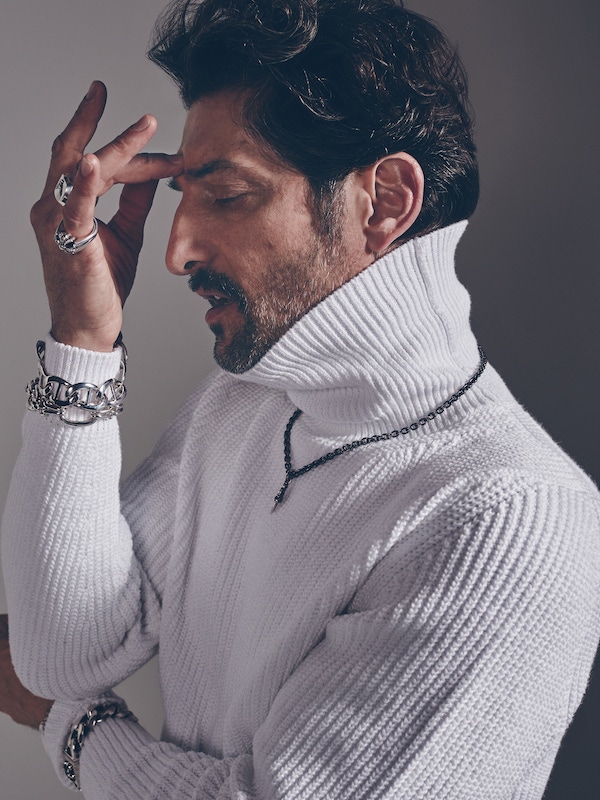 White ribbed cotton roll-neck, Bally; silver large link bracelet and silver oval link bracelet, both  Pomellato 67; oxidised silver chain, dagger pendant, chunky silver chain bracelet, large silver etched skull ring and large silver cross with pavè diamond ring, all Chrome Hearts.