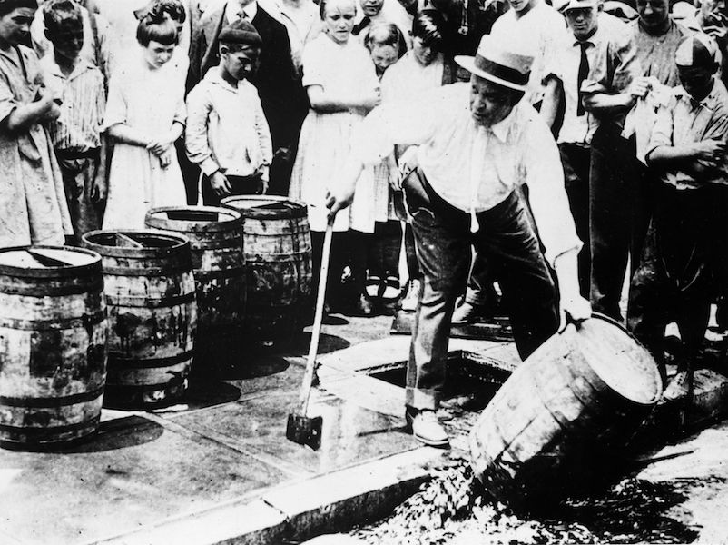 circa 1920:  A man destroying barrels of alcohol during prohibition in America.  Photo by General Photographic Agency/Getty Images.