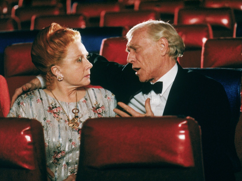 Medium shot of Richard Harris as Frank, wearing tuxedo, facing and with arm around Shirley MacLaine as Helen Cooney; both seated in empty theater. Photo by Warner Bros./Getty Images.