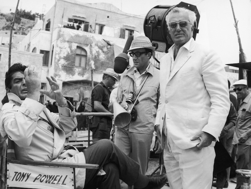 From left to right, actors Victor Mature and Peter Sellers, and Italian director Vittorio de Sica on Ischia, during the filming of 'Caccia alla Volpe' ('After the Fox'), 1965. Mature sits on a chair bearing the name of his character, Tony Powell. Photo by Keystone/Hulton Archive/Getty Images.