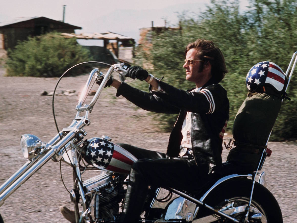 Peter Fonda riding a chopper motorcycle, with a stars-and-stripes helmet on the backrest of his seat, in a publicity still issued for the film, 'Easy Rider', USA, 1969. Photo by Silver Screen Collection/Getty Images.