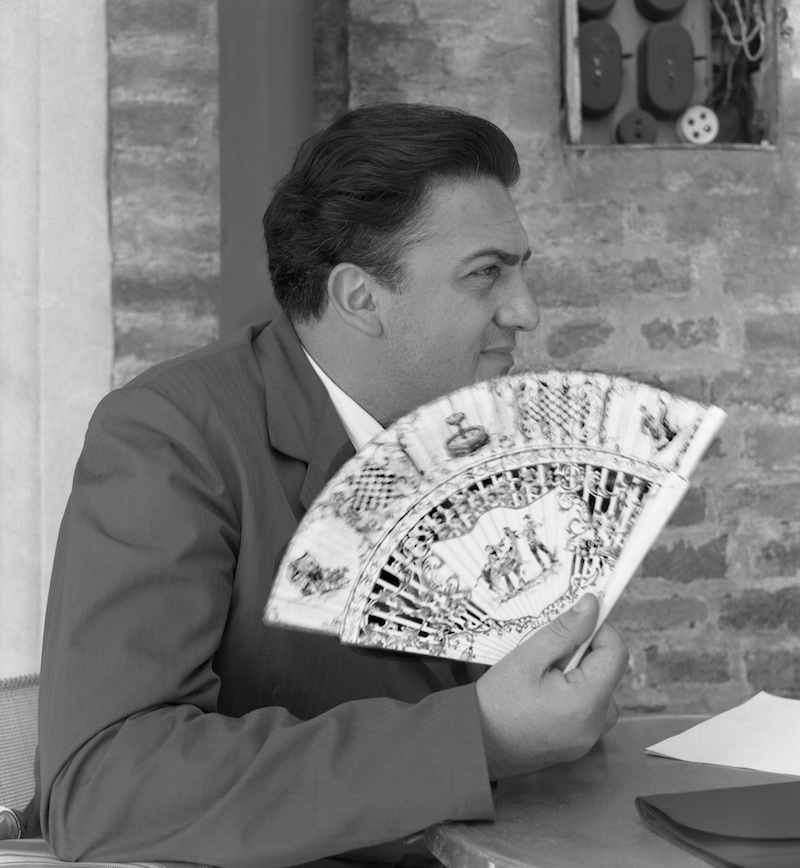 Italian director Federico Fellini wearing a suit, portrayed while holding a fan, Venice, 1954. Photo by Archivio Cameraphoto Epoche/Getty Images.