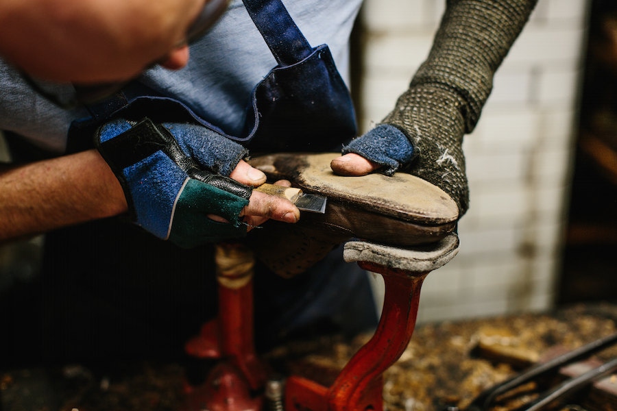 Cutting the sole stitch from an old pair of shoes in the repair room.