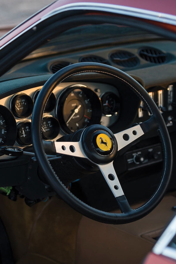 The simple dashboard features numerous circular dials and the large circumference Ferrari three-spoke steering wheel.