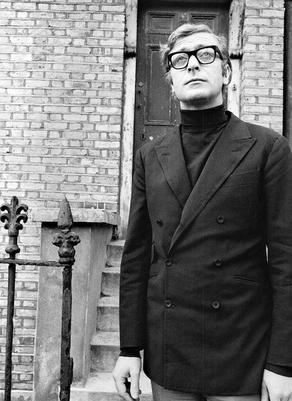 Caine visits his old neighbourhood in 1969 whilst wearing a mod-inspired, high-buttoning 6x2 double-breasted blazer and roll-neck combination.