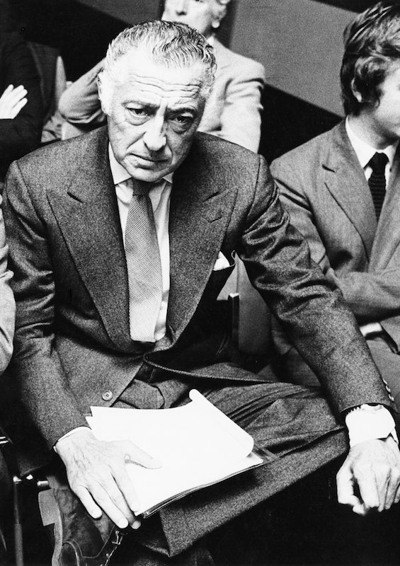 Agnelli wearing a signature grey flannel, peak-lapel suit with suede work boots, circa 1960s. Note his wristwatch, which is being worn on the outside of his shirt cuff.