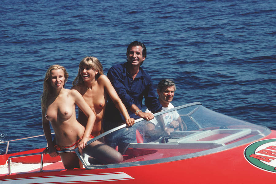 Actor George Hamilton takes off in a speedboat with friends Ruth Luthi and Mike Belami, during a stay in St Tropez, August 1977. Photo by Slim Aarons/Getty Images.