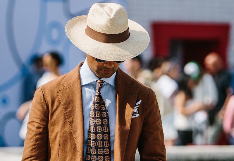 An elegant tobacco linen suit, paired with a printed silk tie and wide-brim Panama hat.