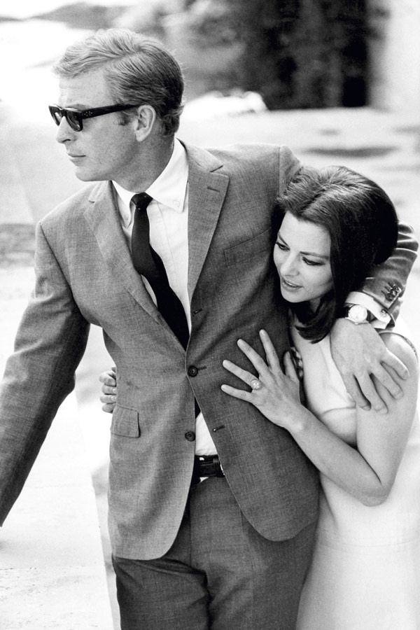 Michael Caine pictured with Giovanna Ralli in 1968. This classic Caine ensemble features a ‘three-roll-two’ suit jacket with slim notch lapels worn without a pocket square, for ultimate pared-back simplicity. Photo by Terry O'Neill/Getty Images