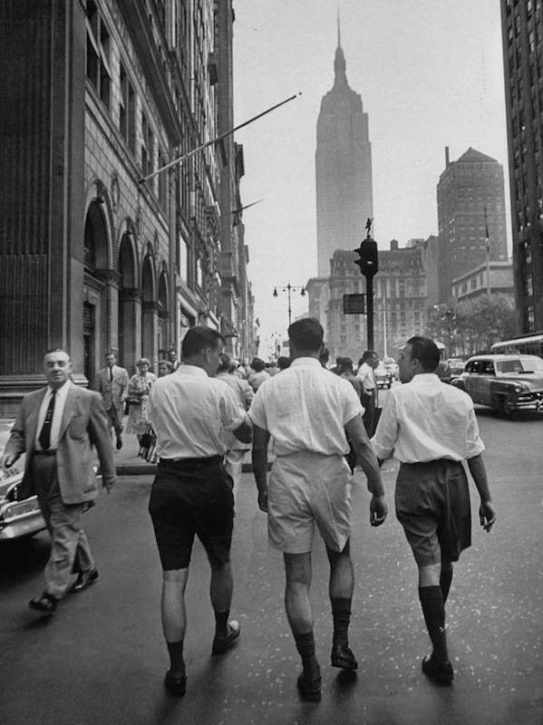 Three young businessmen boldly wearing Bermuda shorts as they walk along Five Avenue, New York City, on their lunch break, 1953.