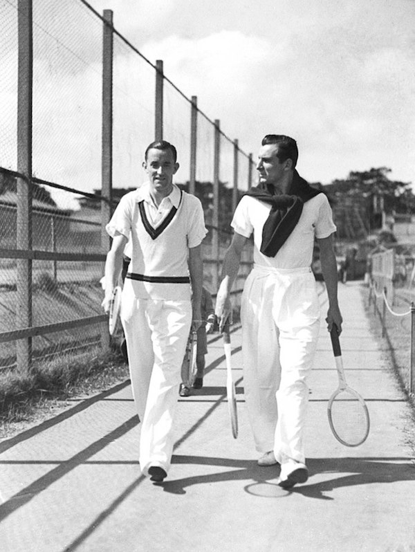 Pat Hughes and Fred Perry in Sydney, 1934. Perry (right) wears voluminous tailored white trousers with a jumper tied over his shoulders.