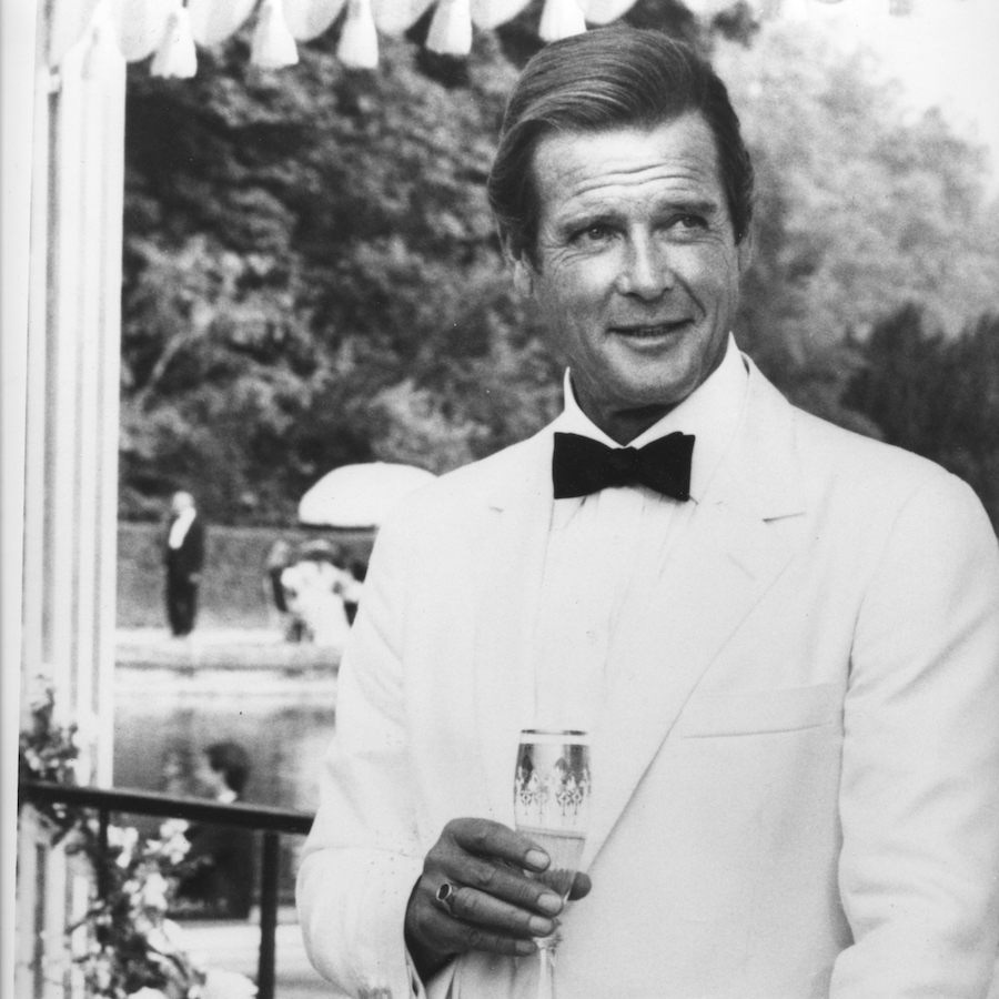 Roger Moore sips Champagne in a white dinner suit as James Bond in A View To A Kill, 1985.