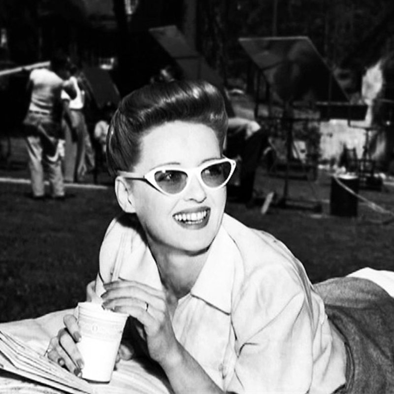 Davis looking cool in the sun wearing white sunglasses and an open-neck shirt, 1942.