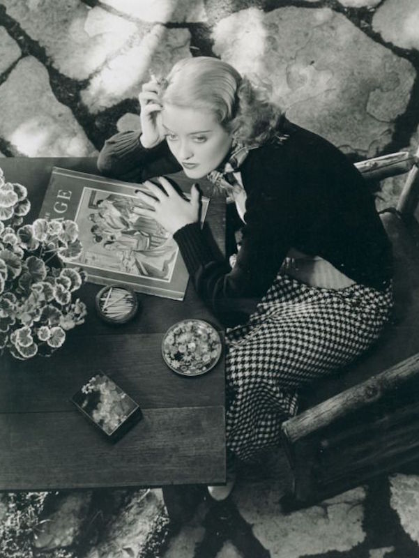 Relaxing in a houndstooth skirt and black cardigan, circa 1930s. Photo by Moviestore Collection/Rex Features.