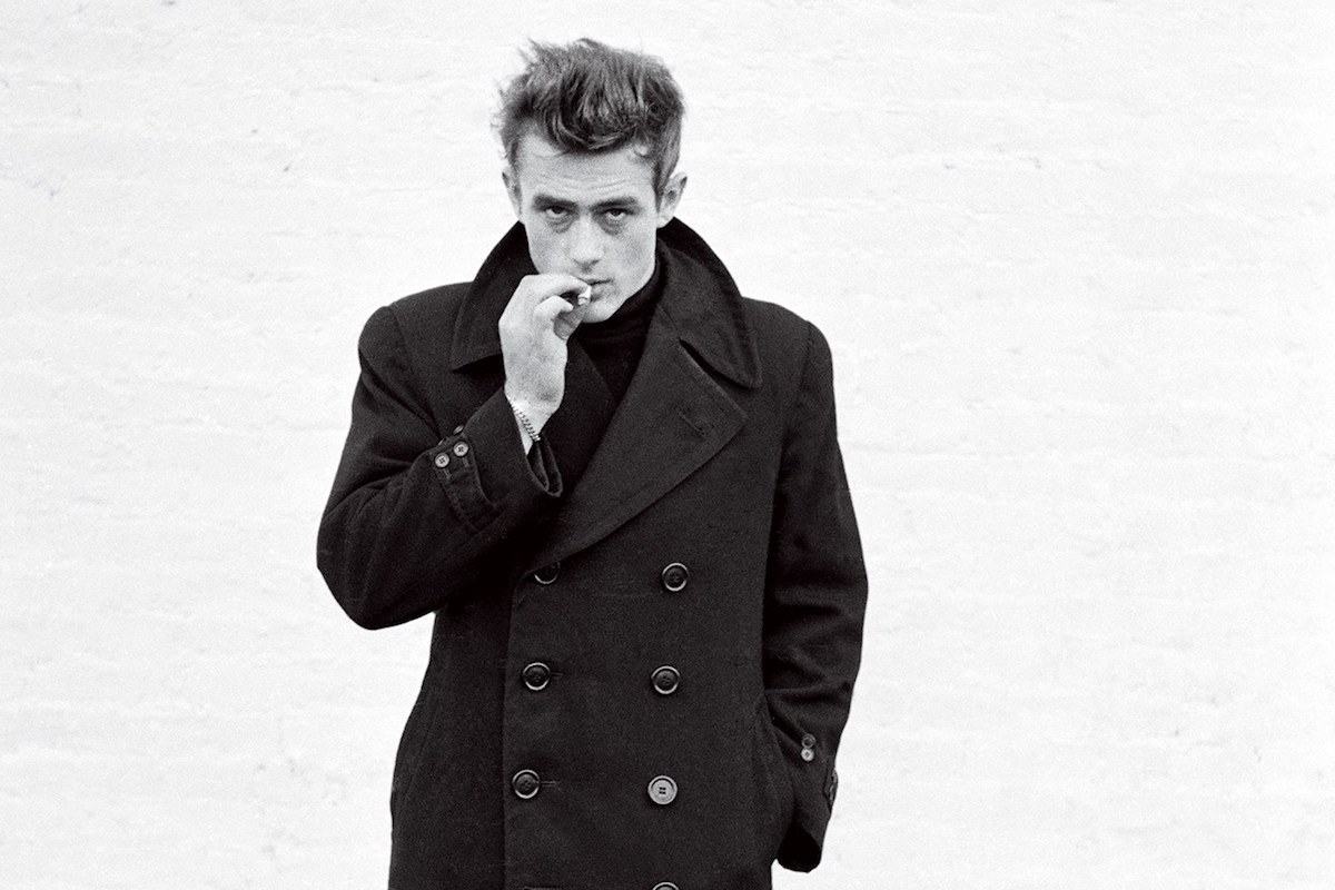 James Dean's overcoat features an eight-button double-breasted closure and adjustable cuffs, worn with a popped collar in New York, 1955. Photograph by Dennis Stock.