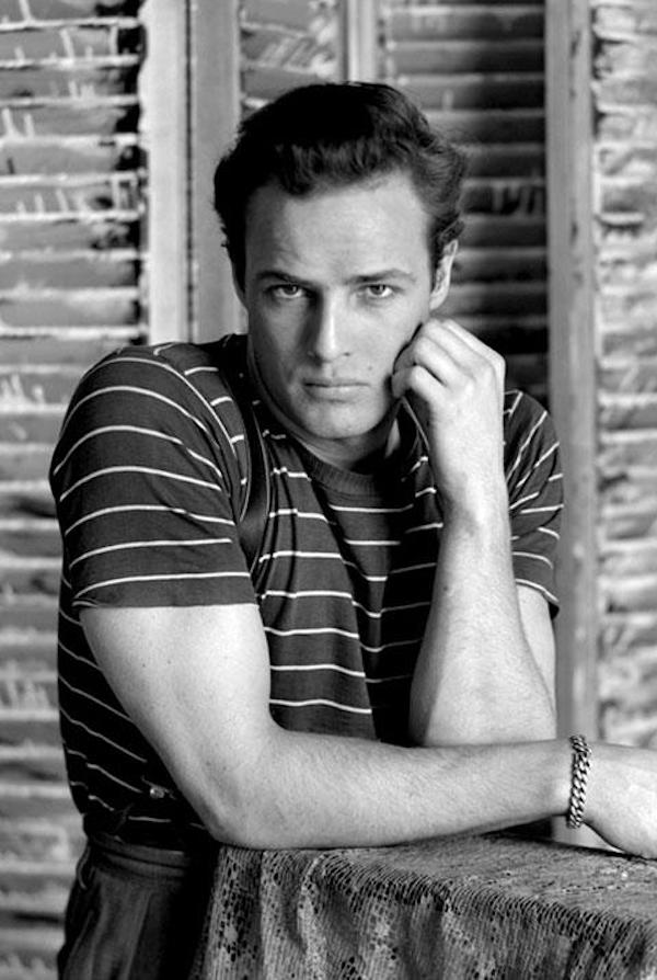 Brando poses in a nautical striped T-shirt worn with high-waisted trousers, circa 1960.