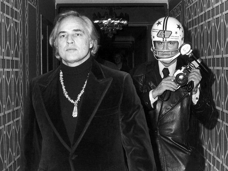 Ron protects himself with a football helmet to photograph Marlon Brando after Marlon reportedly punched him, breaking his jaw. Photo by Got The Shot Prods/Kobal/REX/Shutterstock.