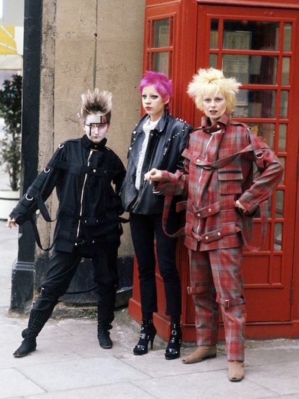 Vivienne Westwood leans against a telephone box with fellow punks in London, 1977, wearing her notorious tartan bondage suit. Image © Corbis.