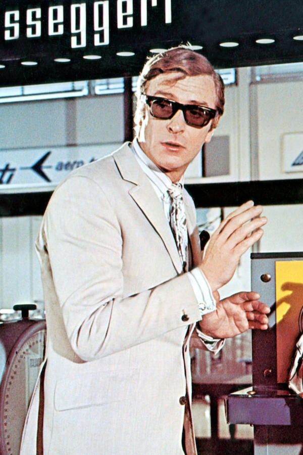 Michael Caine completes a '60s ensemble of a beige linen suit and striped shirt, a pocket square and tortoiseshell sunglasses in The Italian Job, 1969. Photo by Everett Collection Inc/Alamy.