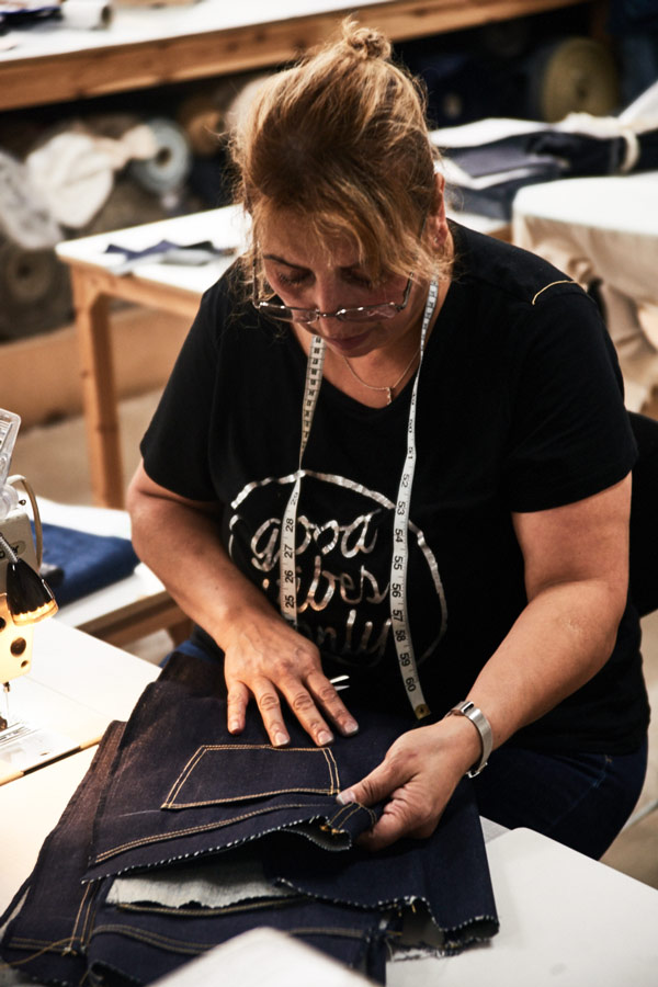 Inspecting the rear pockets. Note the lacking waistband, which is stitched on towards the end of the jean-making process. Photo by Kim Lang.