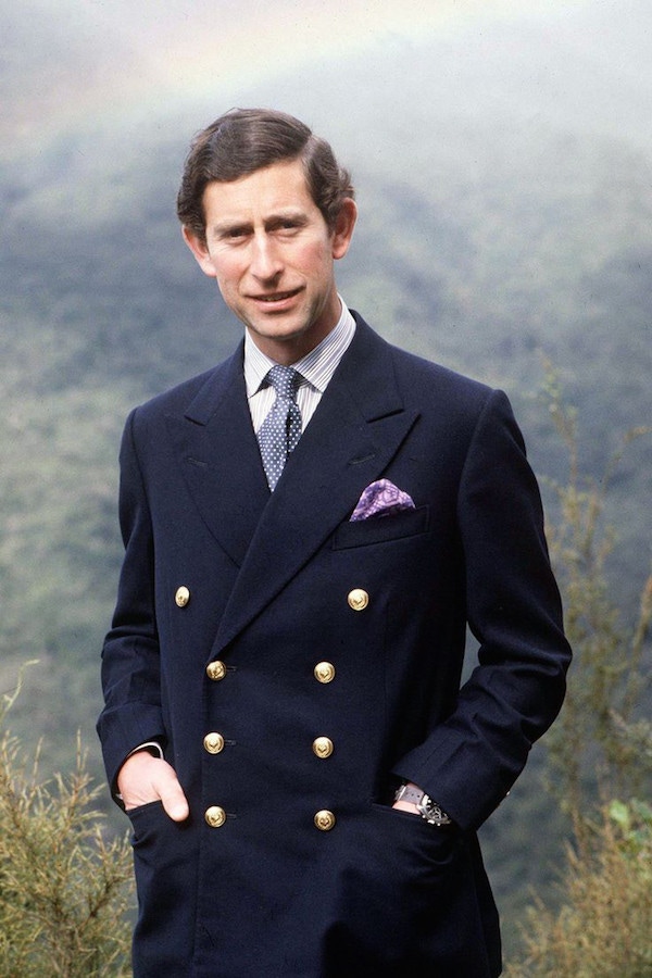 Prince Charles wearing his signature 8x3 double-breasted blazer, finished with gold buttons that nod to the style’s military origins.