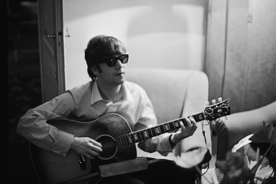 John Lennon of the Beatles plays the guitar in a hotel room in Paris, 1964. Photo by Harry Benson/Express/Hulton Archive/Getty Images.