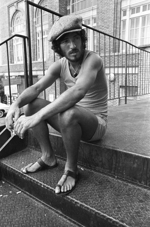 Springsteen looking like the 'New Jersey Che Guevara', wearing a ribbed vest and a baker boy cap while taking a break from the soundcheck at Alex Cooley's Electric Ballroom, 1975. Photograph by Tom Hill/WireImage.