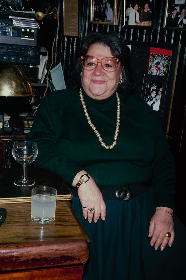 Perched at her long mahogany bar with a glass of wine, 1990. Photo by The LIFE Picture Collection/Getty Images.