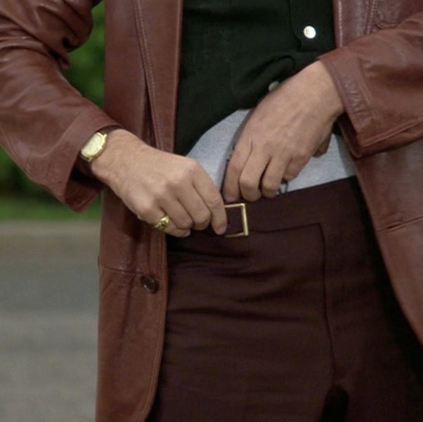 A close-up of Hill’s gold accessories, black shirt and burgundy trousers with an off-centre buckle. Not many people could pull off a leather blazer, but the mobster does so with a generous dose of swagger.