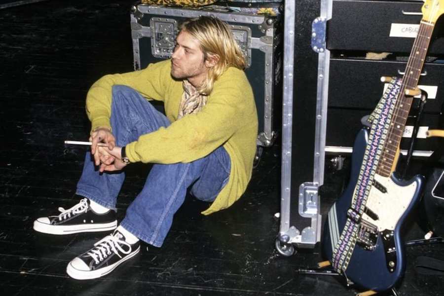Frontman of Nirvana, Kurt Cobain, sits backstage at a concert in New York wearing his Converse All Stars in 1990.