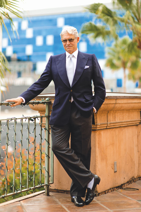 Michael Nouri demonstrates lighter coloured socks with a tonal ensemble of wide-legged charcoal trousers, pale blue ribbed hosiery and black leather slip on shoes.