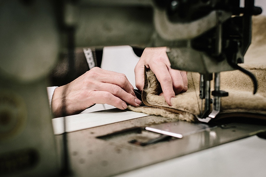 Hand-sewing pieces of shearling together.