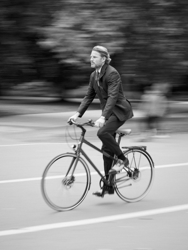 Blue wool double-breasted suit jacket, Canali; navy nylon-elastane jogging trousers, burgundy Le Flâneur d’Hermès bicycle, both Hermès; blue cotton Oxford shirt, navy cotton-cashmere spotted sleeveless cardigan, both Brooks Brothers; blue wool tie, navy patterned silk scarf, both Budd Shirtmakers; Ebury navy calf-leather and stone canvas double-monk-strap shoes, Crockett & Jones; Radiomir 1940 3 days automatic Titanio 45mm timepiece, Panerai.