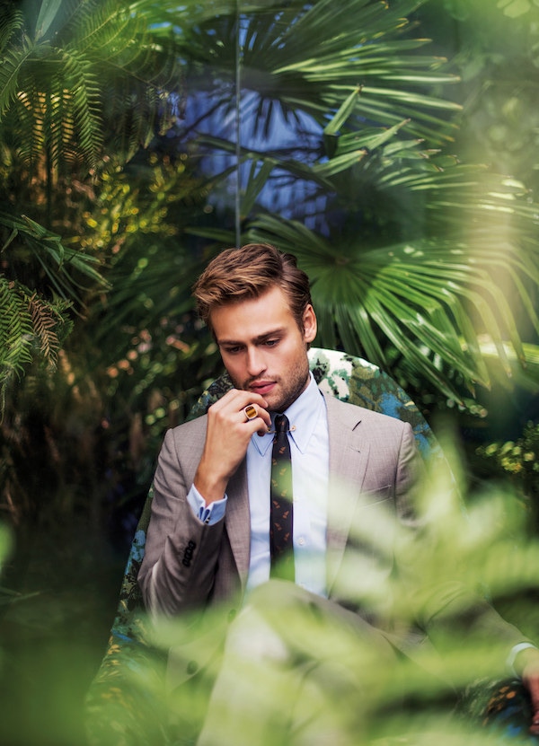 Light grey cotton two-piece suit, Emporio Armani; powder blue cotton shirt and yellow-gold collar pin, both Edward Sexton; black and copper silk feather print tie, The Kooples. Silver-set tiger's eye ring, property of Douglas Booth.
