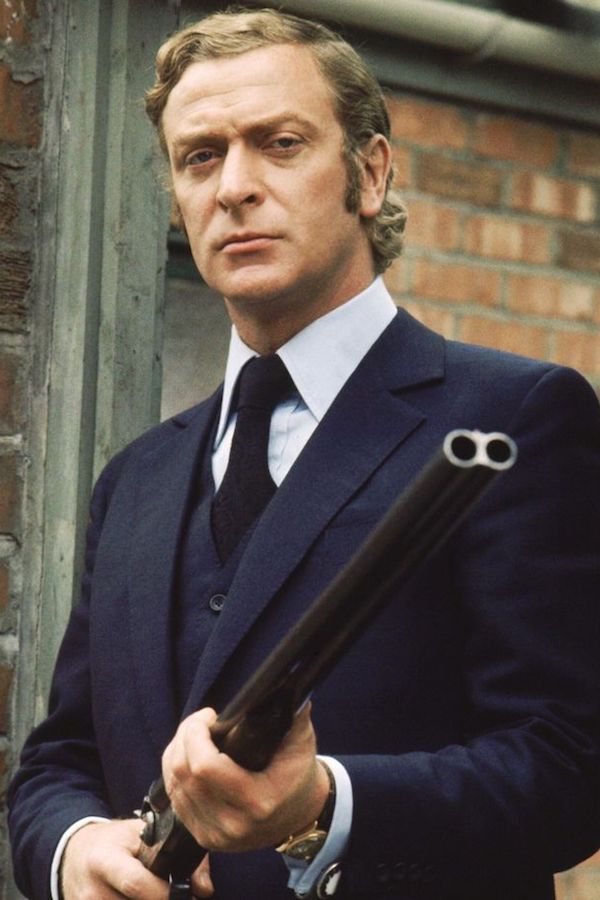 Caine wears a bespoke three-piece suit with slanted pockets, a high notched lapel and a single-breasted waistcoat as Jack in Get Carter, 1971. The accessories of a blue long-sleeved shirt with double cuff, oversized gold and white cufflinks, dark blue silk tie with diagonal rib and Rolex Oyster Day-Date with a brown leather strap all make their contribution to a truly imperious whole.