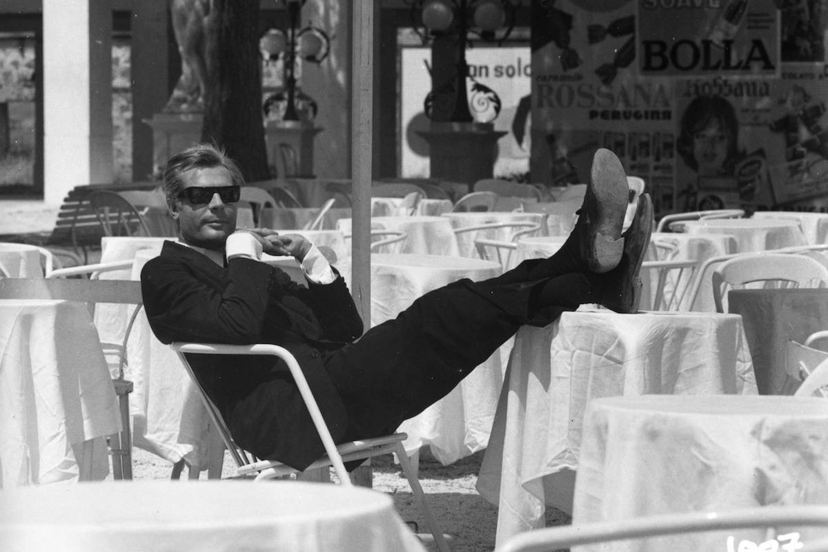 Marcello Mastroianni wears a classic black single-breasted suit, white shirt and retro sunglasses as Guido Anselmi in the film 8½, 1963.