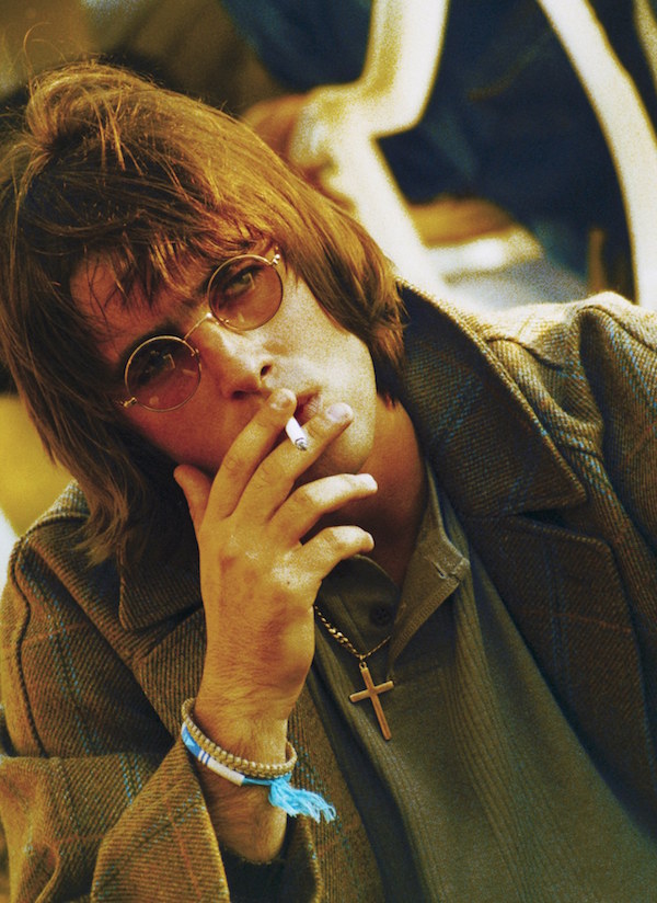 Gallagher channels John Lennon with round glasses and a cigarette in Finsbury Park, 1996. Photo by Jadranka Krsteska/Redferns.