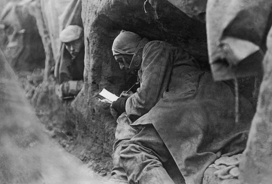 A British soldier savours a chance to write home whilst sheltering in a trench.