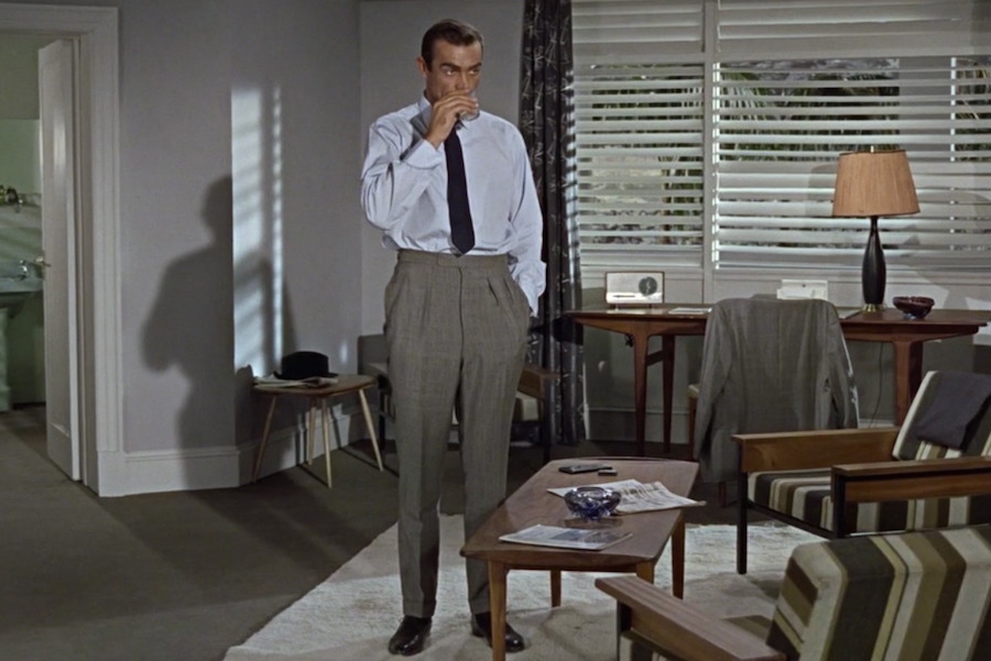 Sean Connery’s James Bond shows another way to wear wide trousers in Dr No, 1960. Although high-waisted and with twin pleats, the trousers taper gently down to a narrow opening, giving them more of a contemporary feel even today.