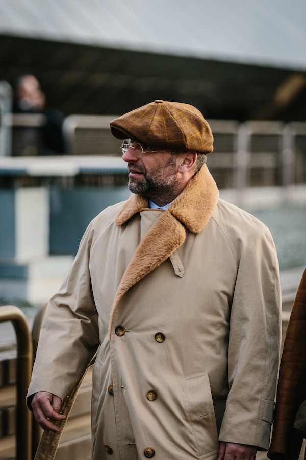 A gentleman in Florence wears a brown peaked cap with a large gold overcheck and tonal shearling coat. Photo by Jamie Ferguson.