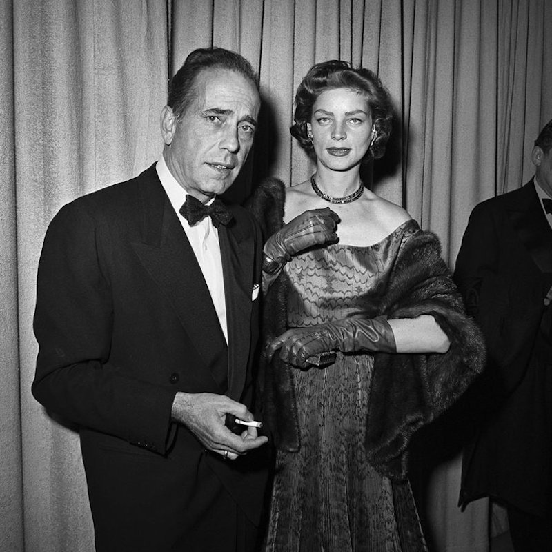 Humphrey Bogart looks effortlessly cool wearing black tie at the Academy Awards ceremony with his wife Lauren Bacall in Los Angeles, 1952. Photograph by Frank Worth, Courtesy of Capital Art/Getty Images.