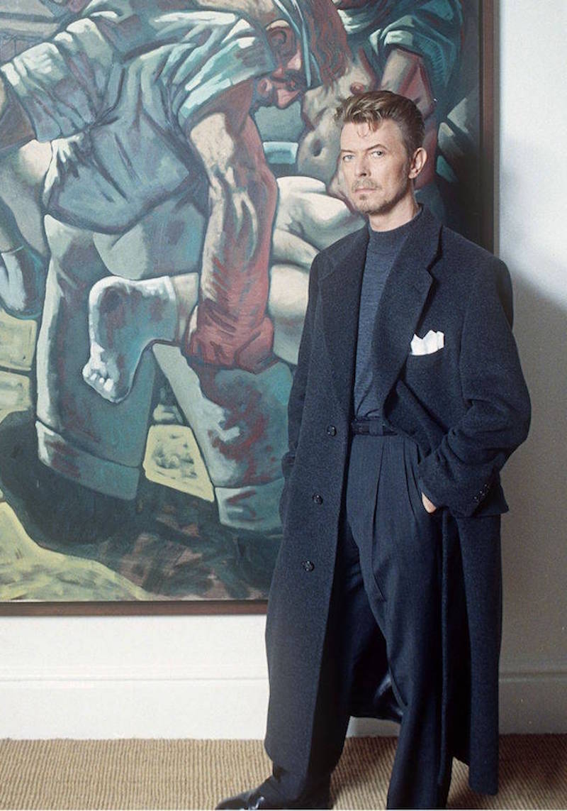 David Bowie was often photographed in trousers featuring deep pleats and wide legs. Here, he wears a tonal blue ensemble at the British Museum, 1994.