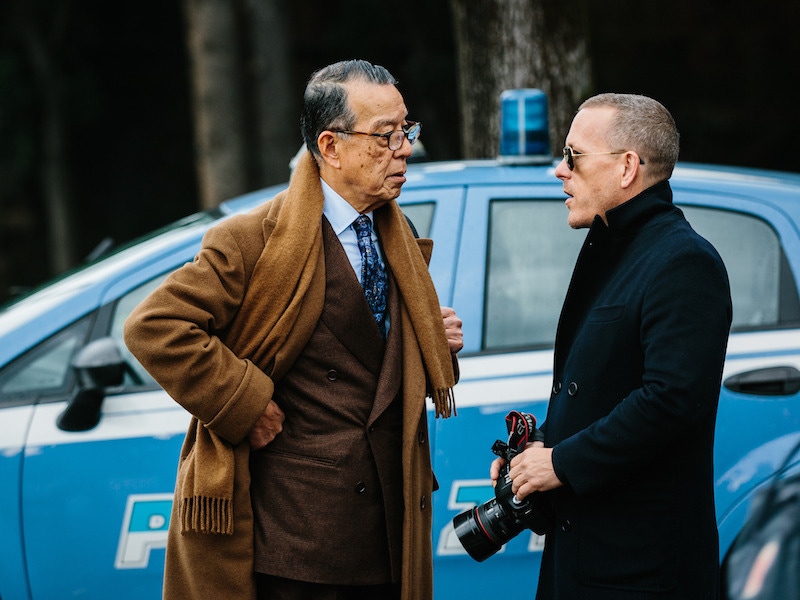 Yukio Akamine wears a double-breasted chocolate flannel suit with a light blue poplin shirt as he speaks with the master of street-style photography, Schott Schuman.