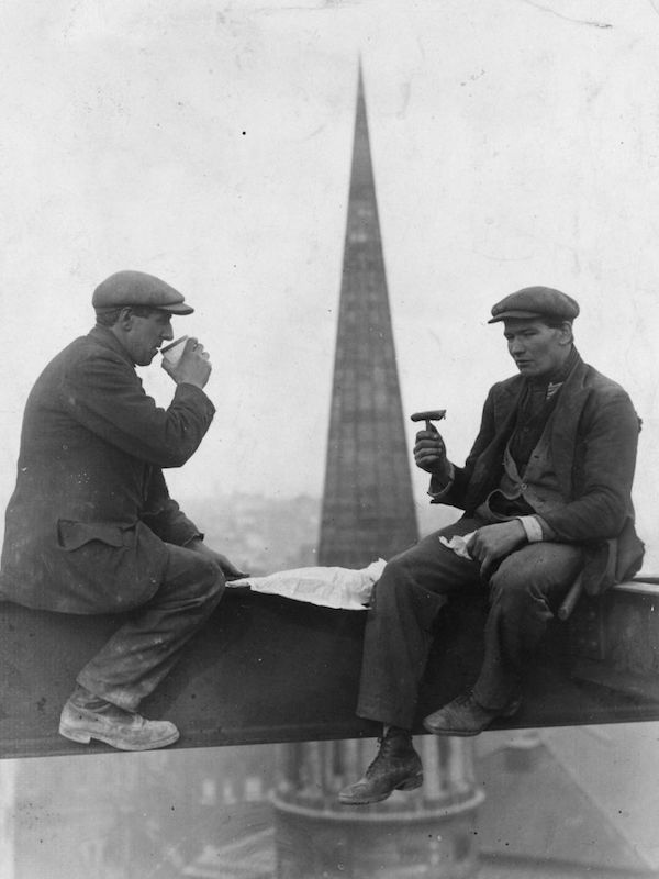 Two roofers take a break for lunch in front of the spire of All Souls Church, London, circa 1940. Their tailored jackets have patch pockets, peaked lapels and enough movement to allow them to work without constraints.